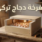 مفرخة دجاج تركي منزلية الصنع مفتوحة الغطاء تظهر بداخلها البيض ومصباح التدفئة ومقياس الحرارة على طاولة خشبية مع أدوات التصنيع